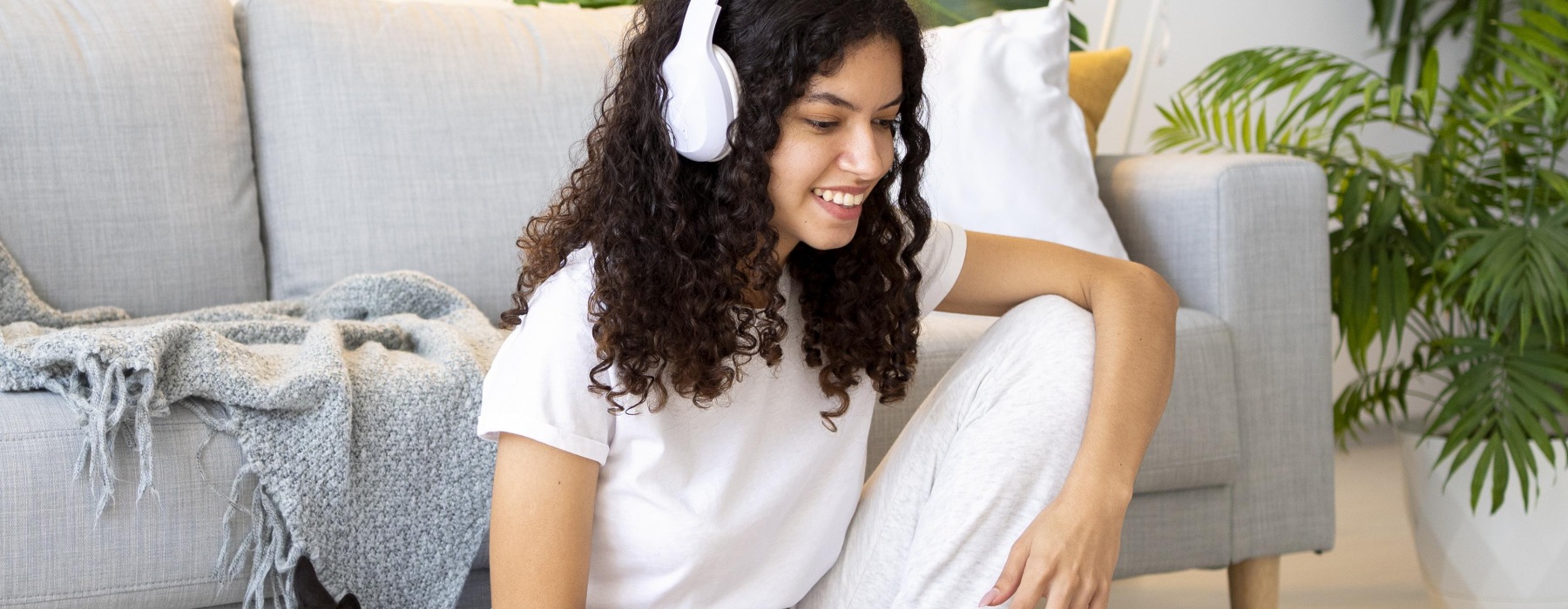 Woman sitting on the floor in her apartment with headphones on