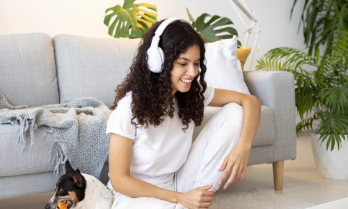 Woman sitting on the floor in her apartment with headphones on